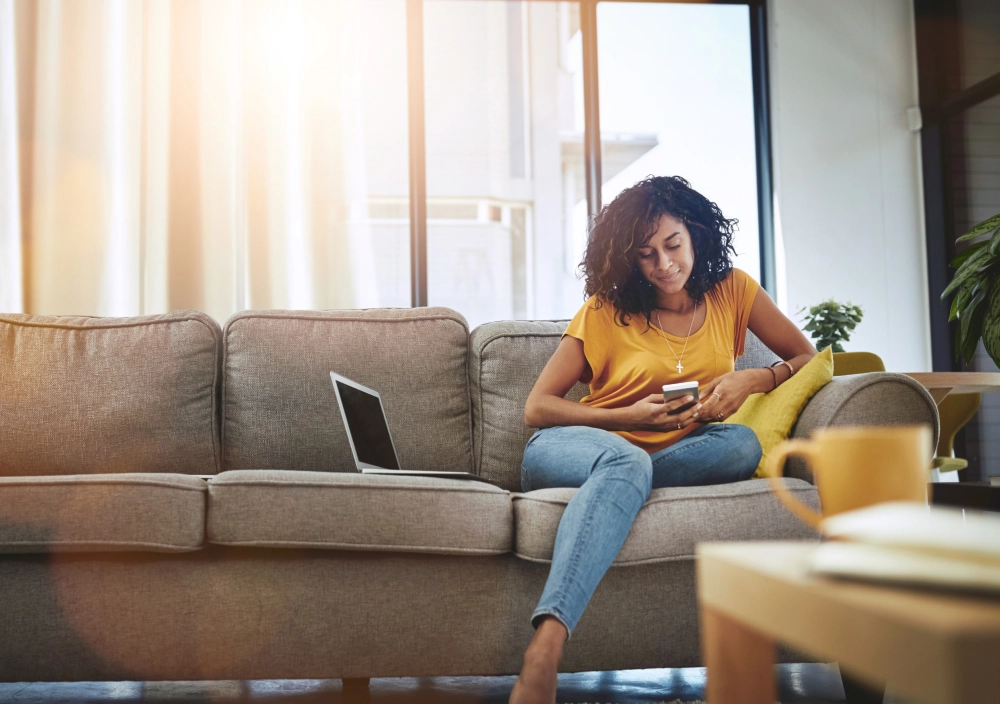 Woman on sofa with smartphone and laptop