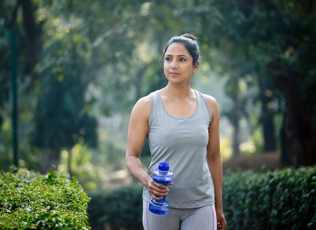 Woman walking in park with water bottle