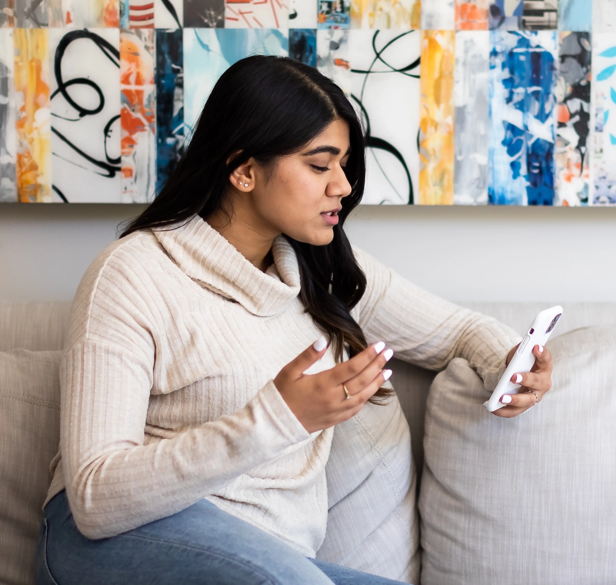 Woman using her phone for a telehealth visit on her couch