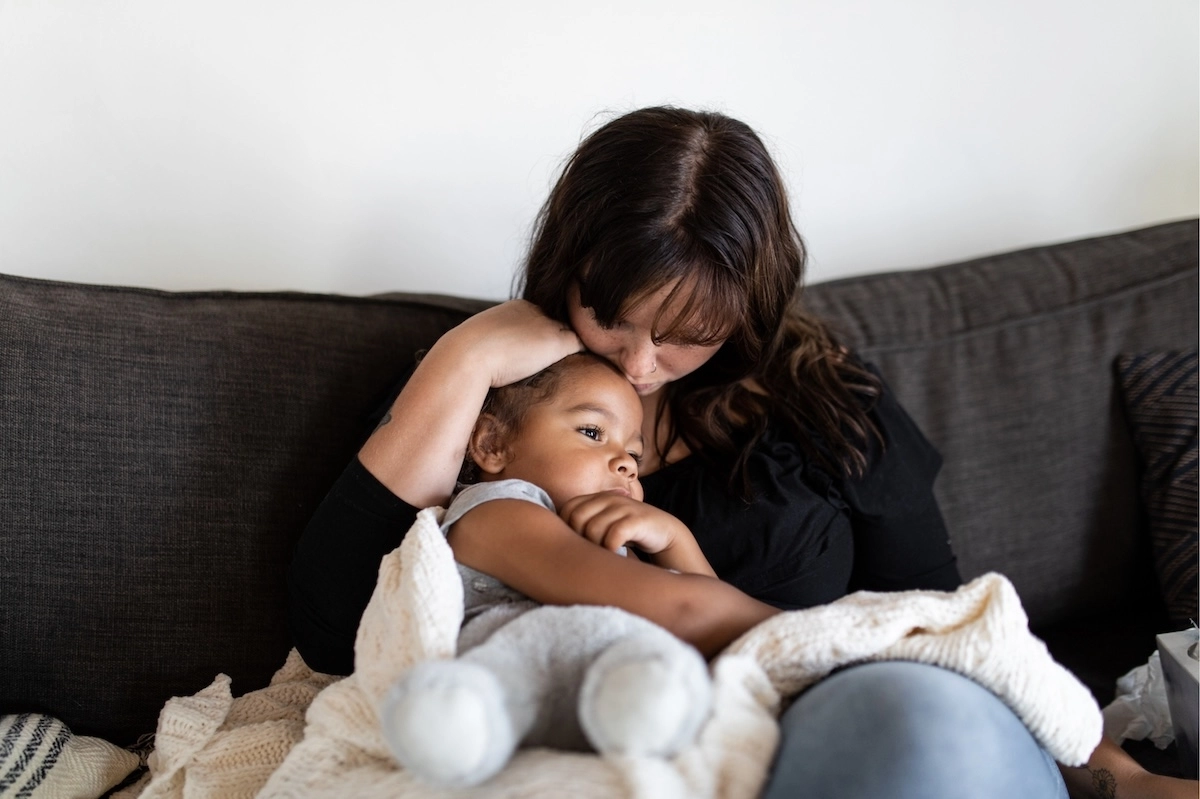 mom holding sick child on the couch