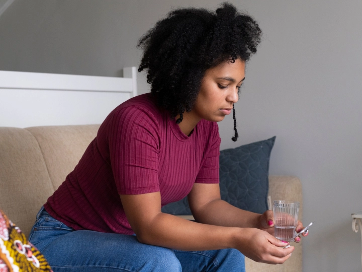 woman sitting on edge of couch feeling nauseous