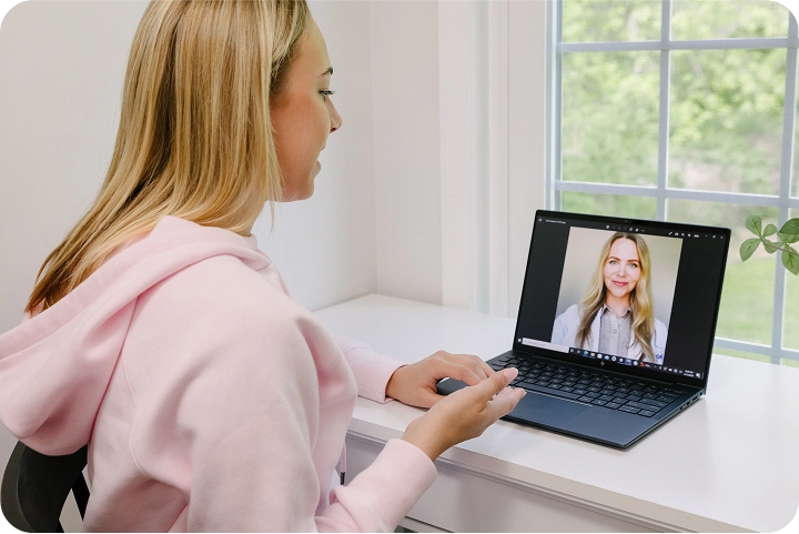 young woman sitting at desk having an online therapy session.