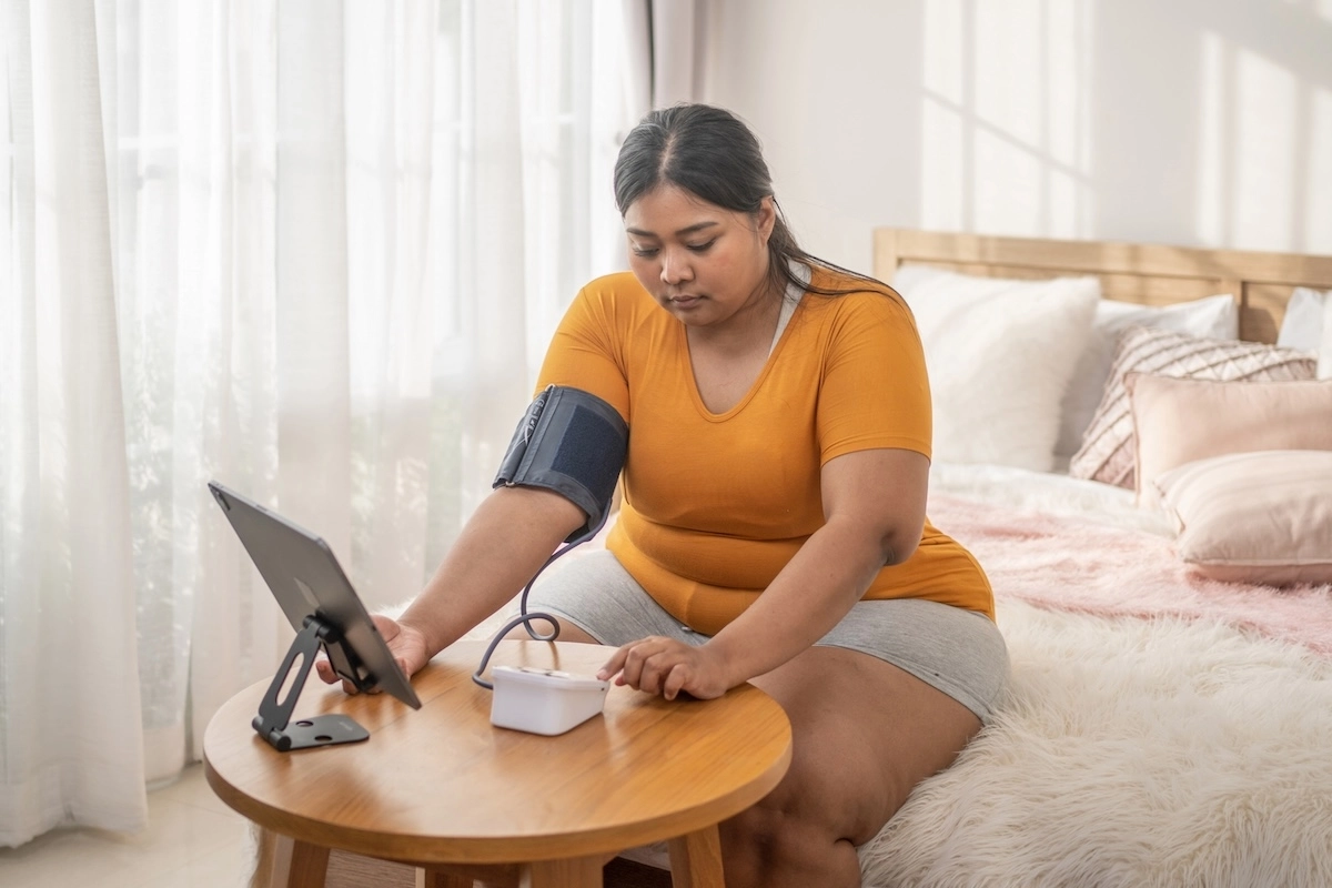 woman on couch taking her own blood pressure