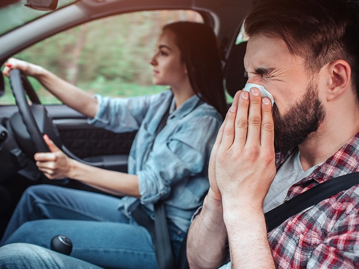 Man with allergies blowing his nose in a car
