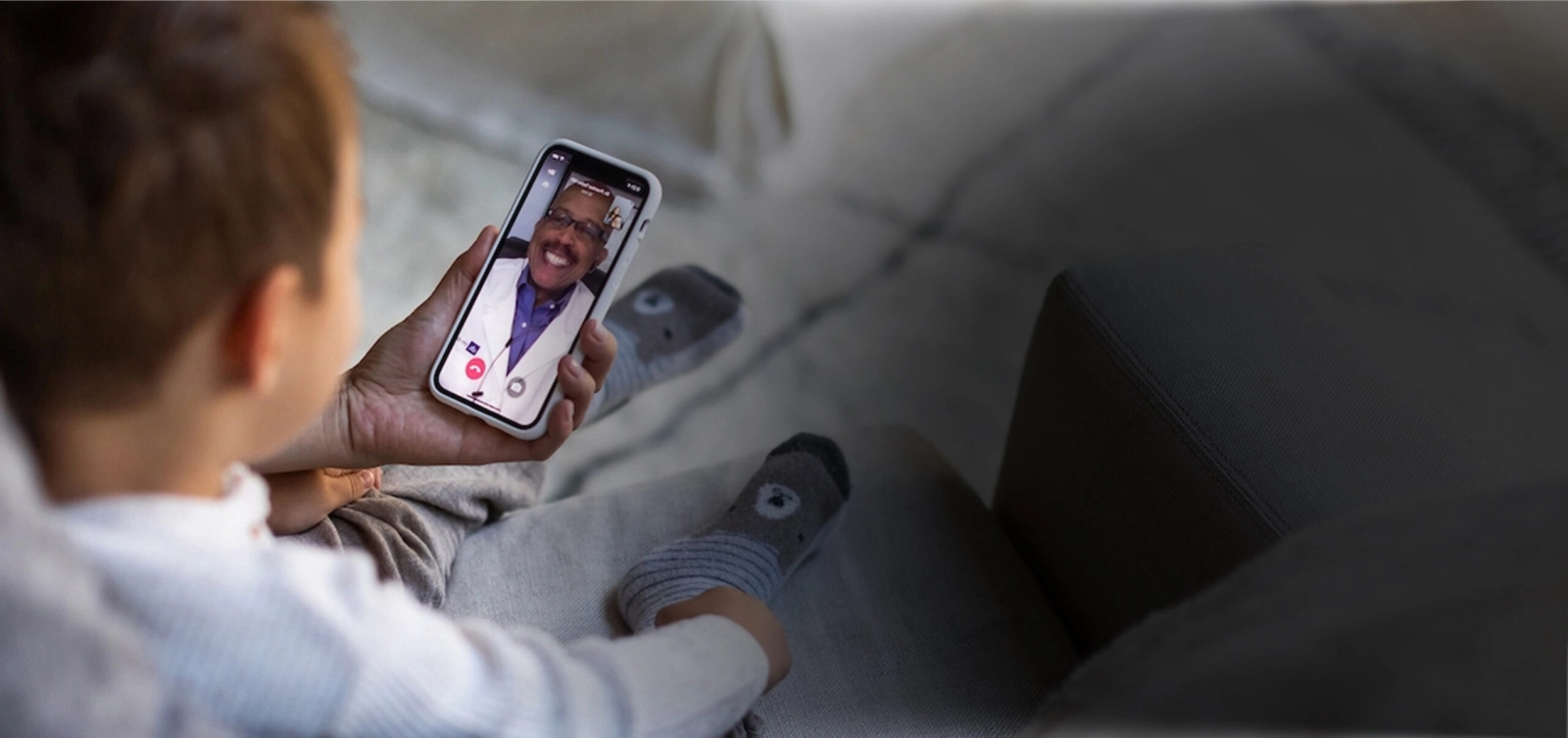 hand holding smartphone and small child in telemedicine conversation